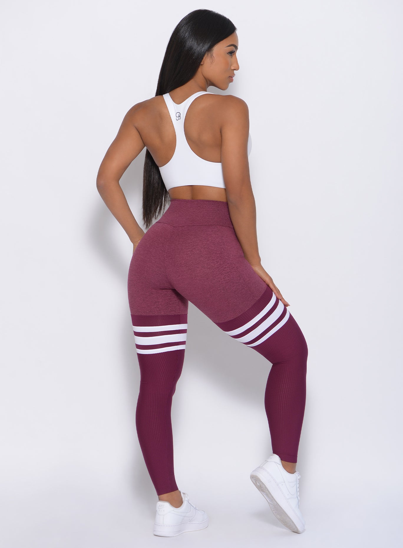 Back view of the model with her left hand on thigh wearing our white Bralette and a high waist leggings in Burgundy Rose