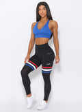 Model looking forward wearing our high waisted Scrunch Thigh high in black with three stripes on the thighs and a black sports bra