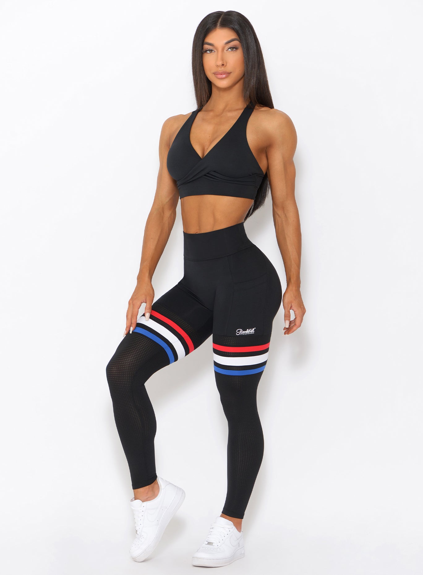 Three quarters view of the model wearing our Scrunch Thigh high in black with three stripes on the thighs and a black sports bra