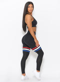 Right side view of the model wearing our high waisted Scrunch Thigh high in black with three stripes on the thighs and a black sports bra