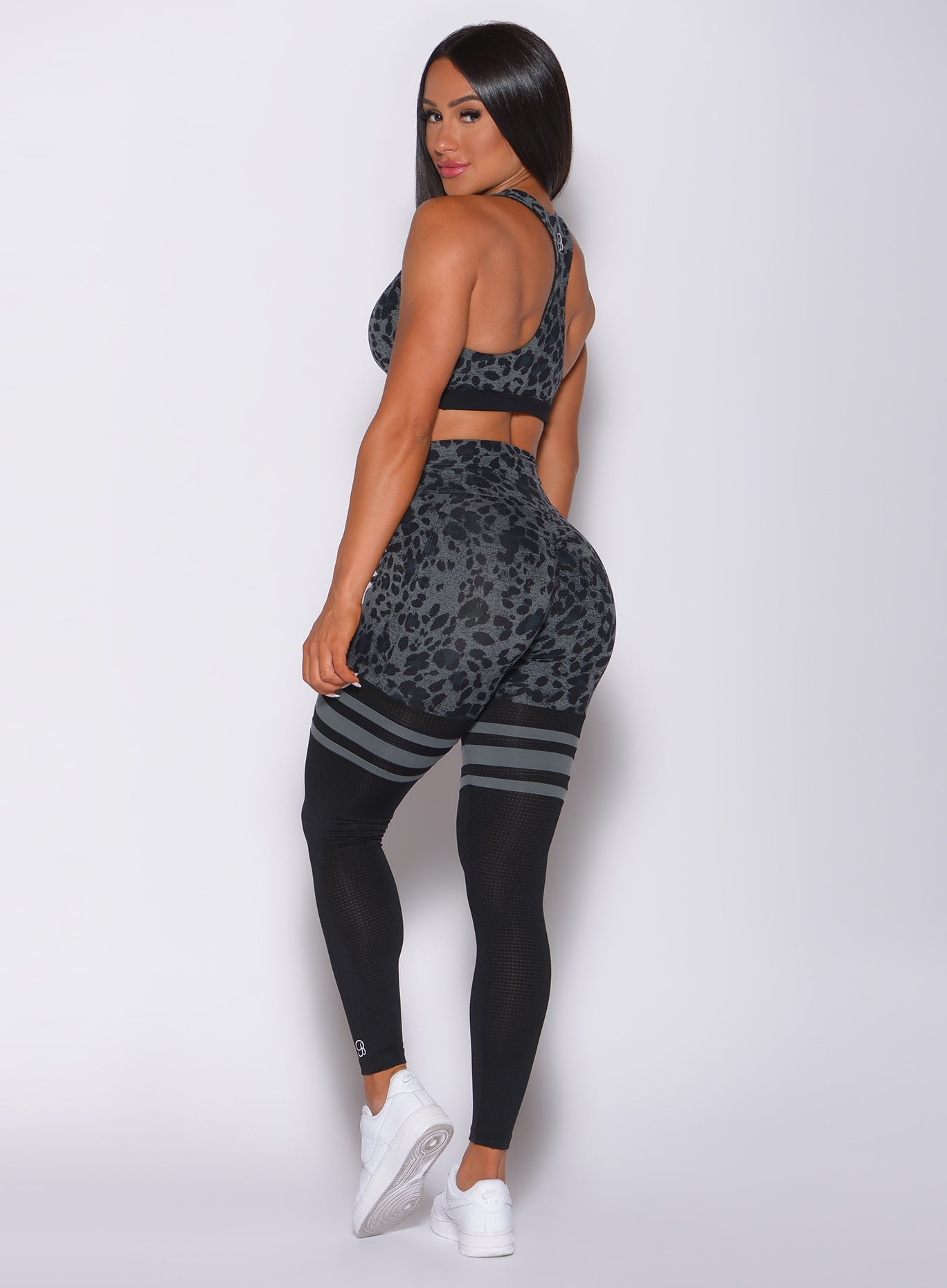 Left side profile view of a model facing to her left wearing our scrunch thigh high in charcoal leopard print and a matching bra