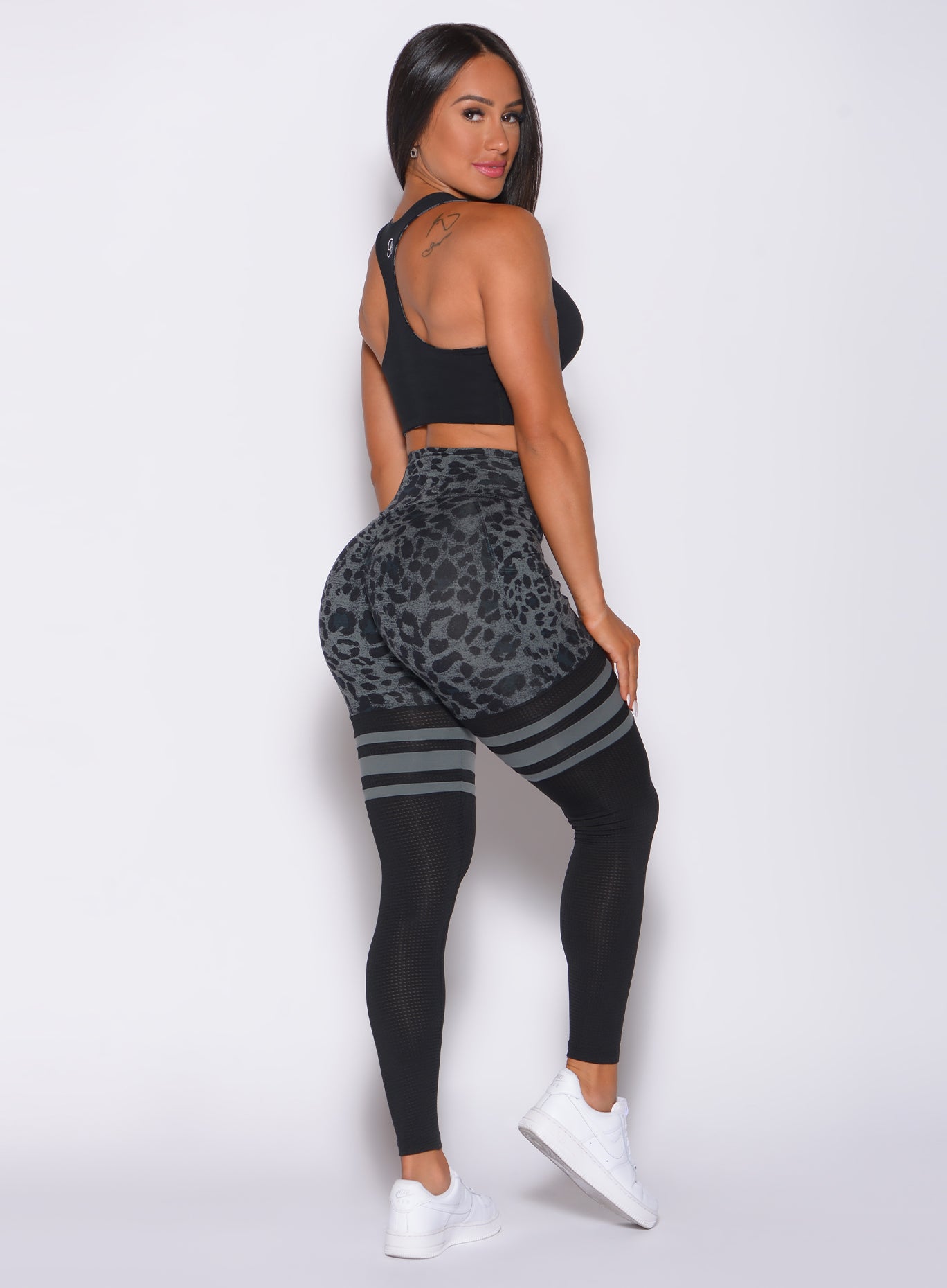 Right side profile view of a model facing to her right wearing our scrunch thigh high in charcoal leopard print and a matching bra