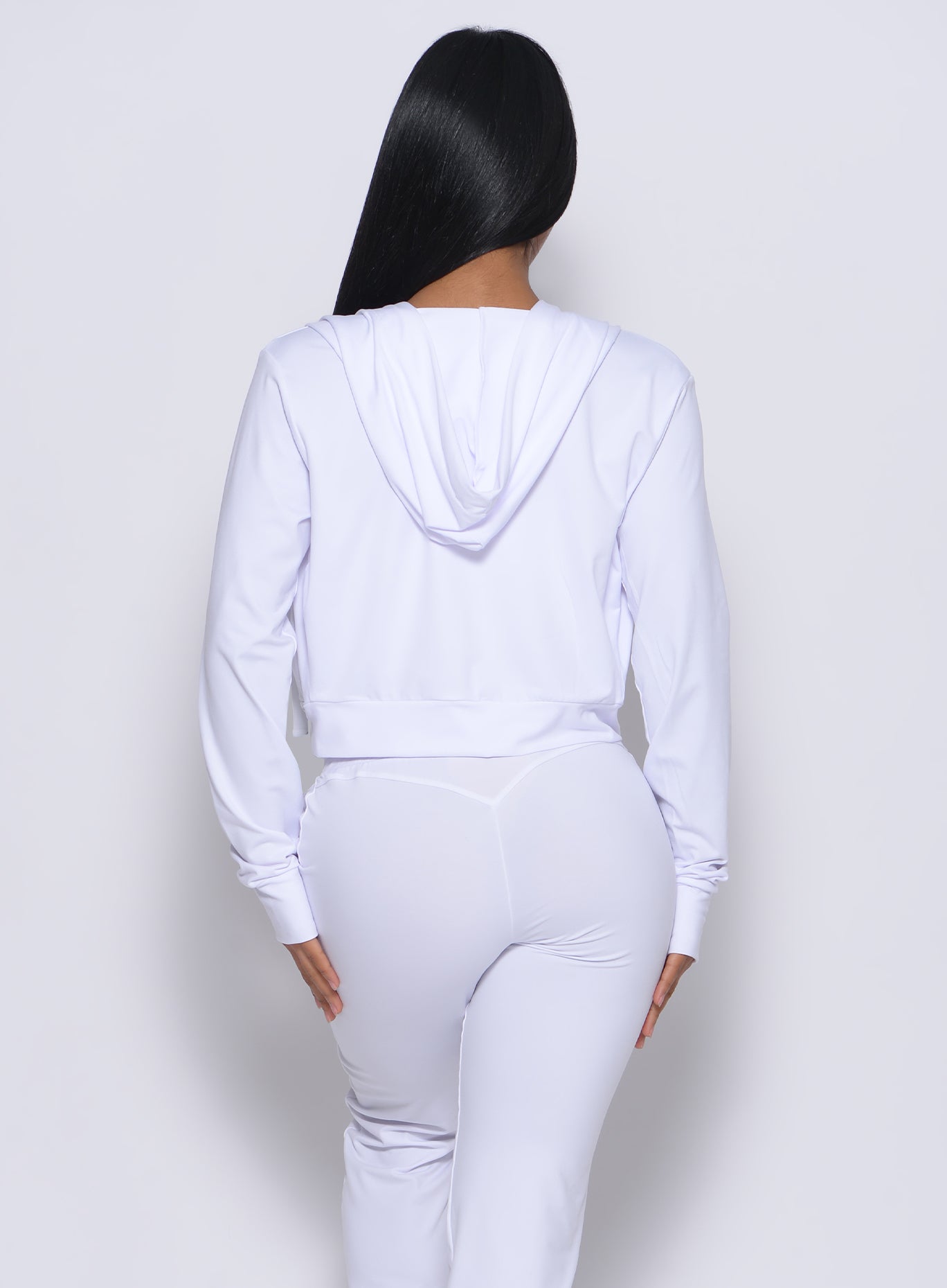 Back profile view of a model in our white signature jacket and a matching leggings
