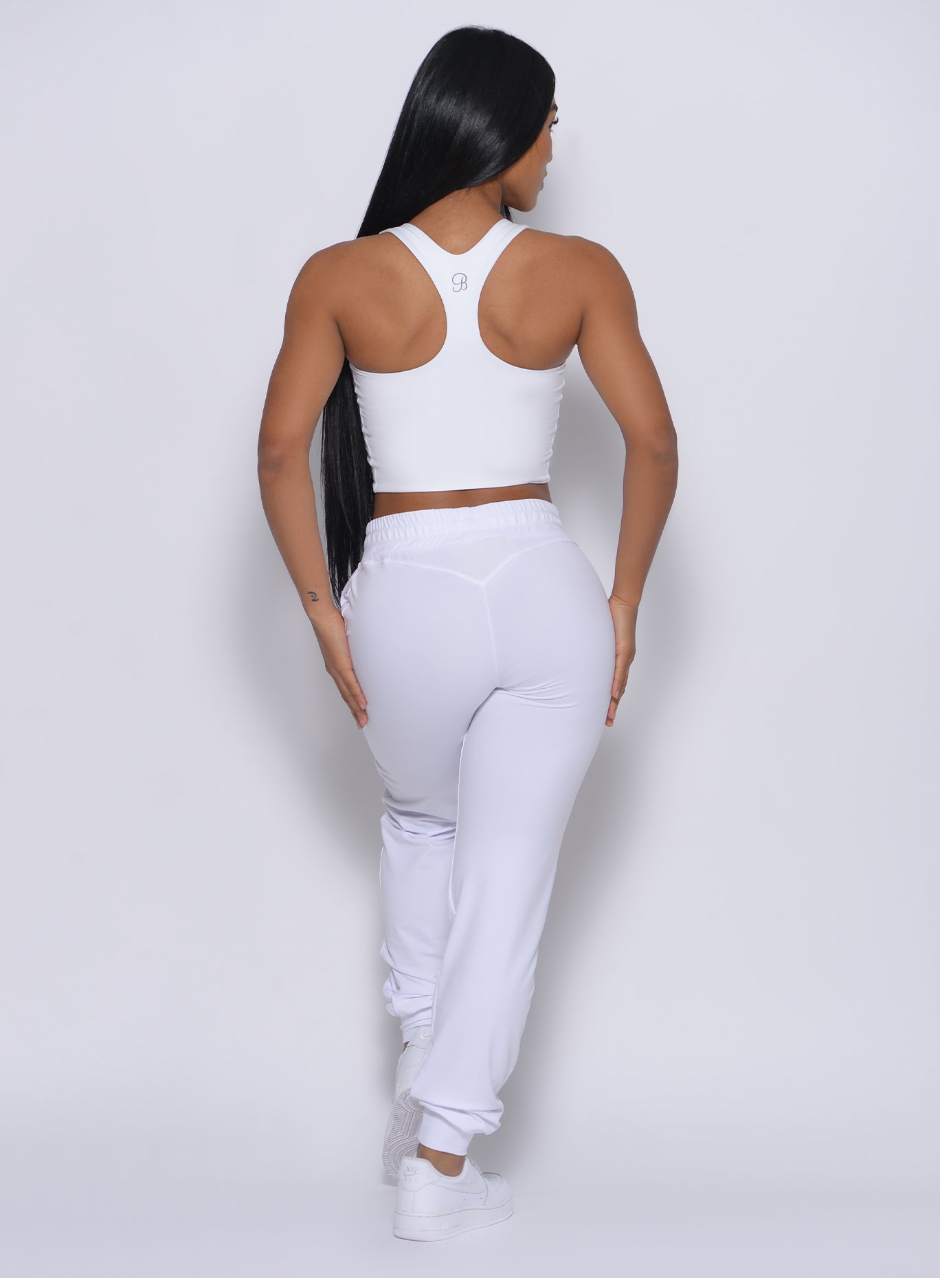 Back profile view of a model in our white elevated tank bra and a matching joggers