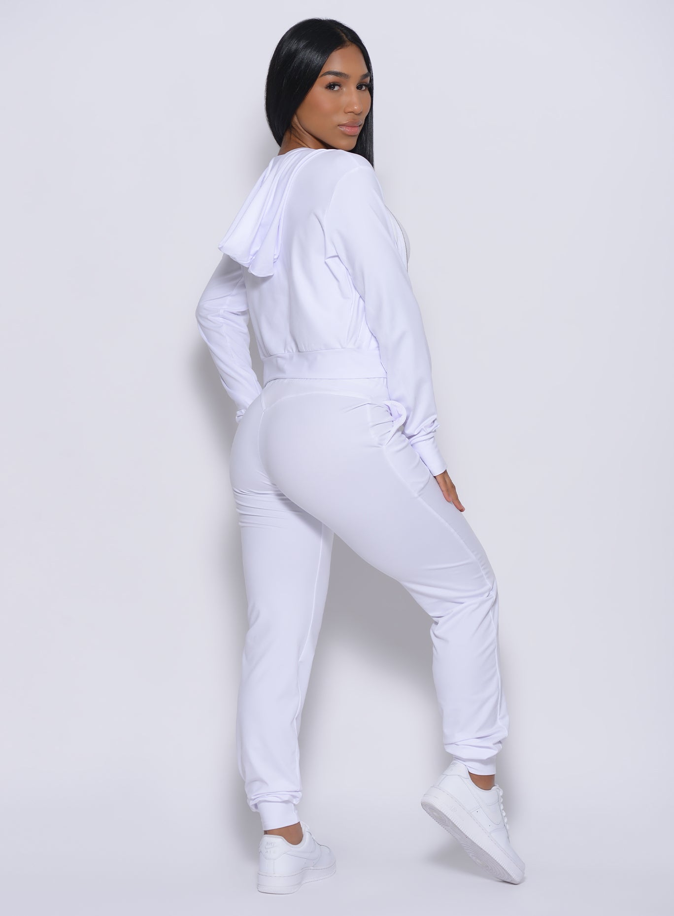 Right profile view of a model facing to her right wearing our white signature jacket and a matching joggers