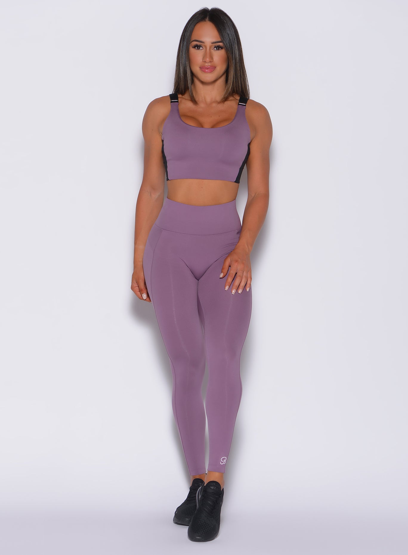 Front profile view of a model in our snatched waist leggings in violet frost color and a matching sports bra