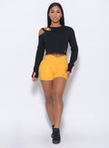 Front profile view of the model in our tiny waist shorts in sunkissed color and a black pullover