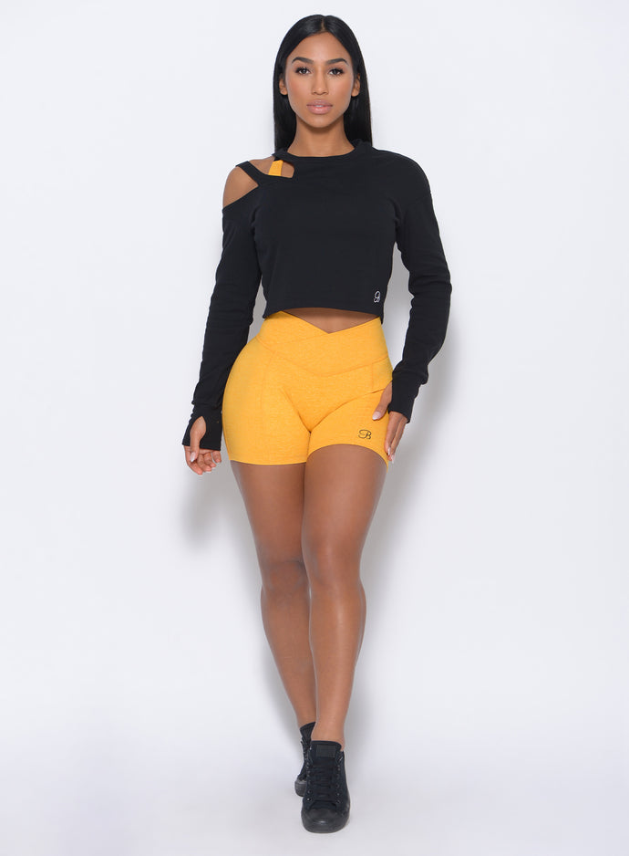 Front profile view of the model in our tiny waist shorts in sunkissed color and a black pullover