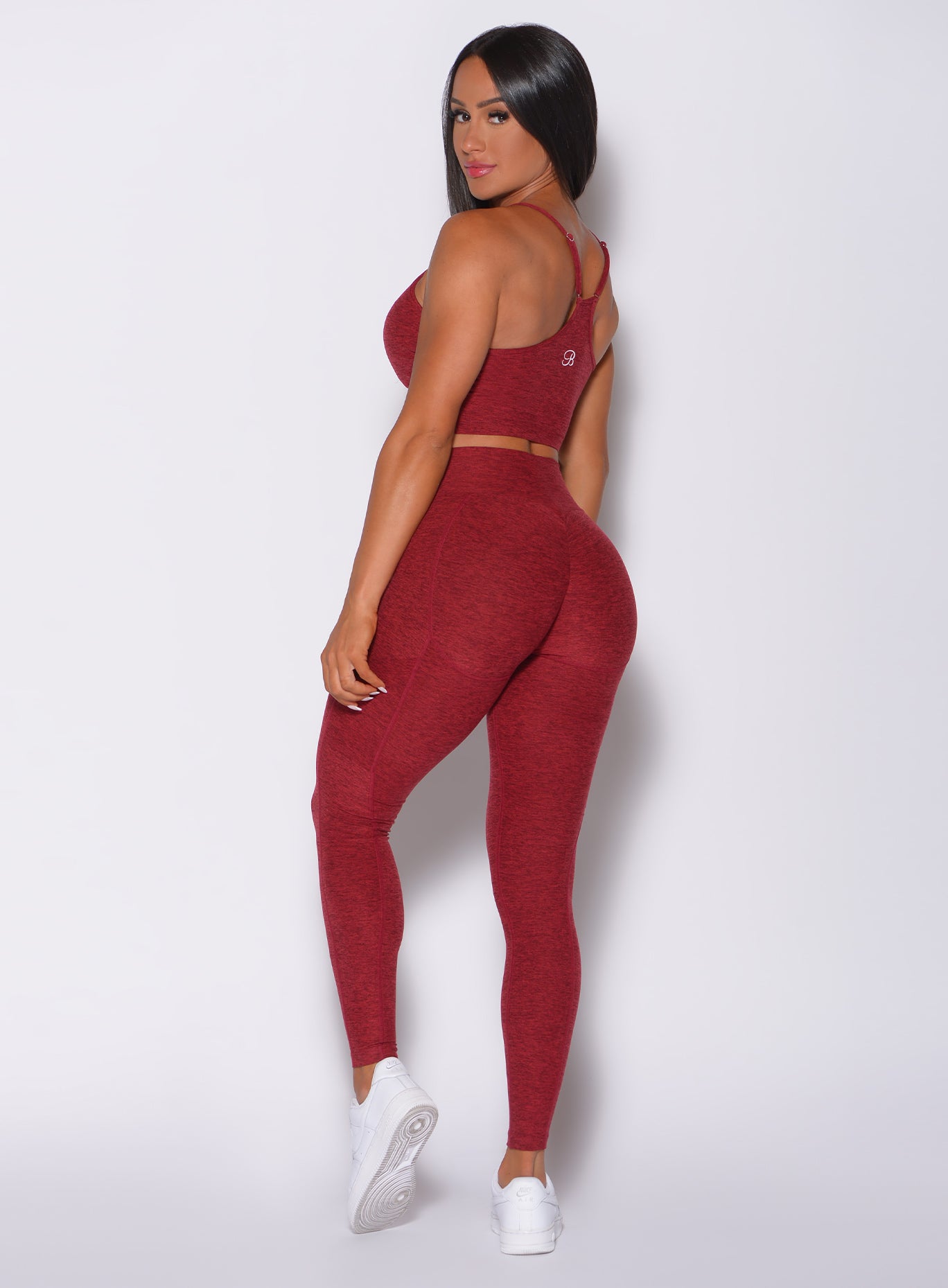 Left side profile view of a model wearing our uplift pocket leggings in red rose color and a matching bra