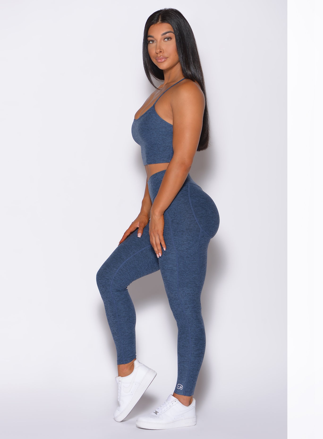 Left side profile view of a model facing to her left wearing. our uplift pocket leggings in night sky color and a matching bra