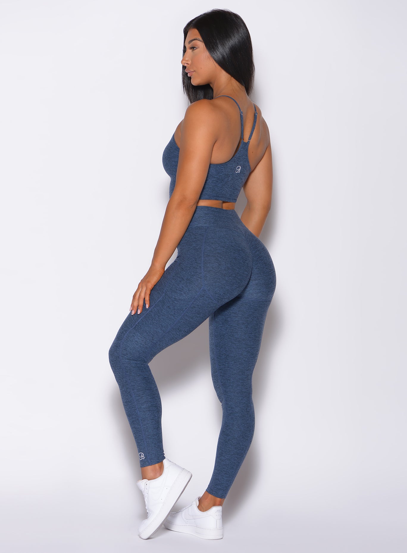 Back profile view of a model angled right wearing our uplift pocket leggings in night sky color and a matching bra
