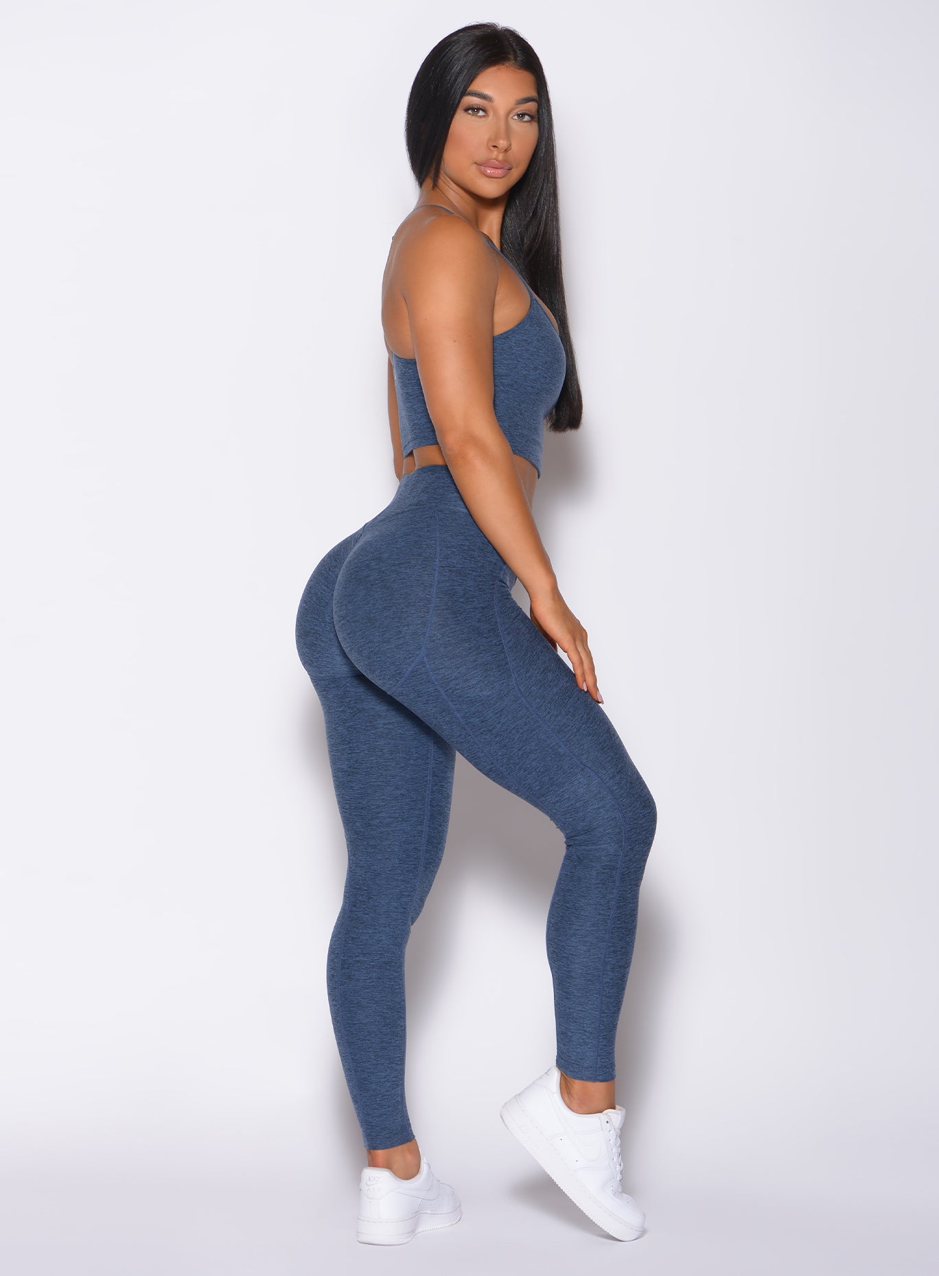 Right side profile view of a model in our uplift pocket leggings in night sky color and a matching bra