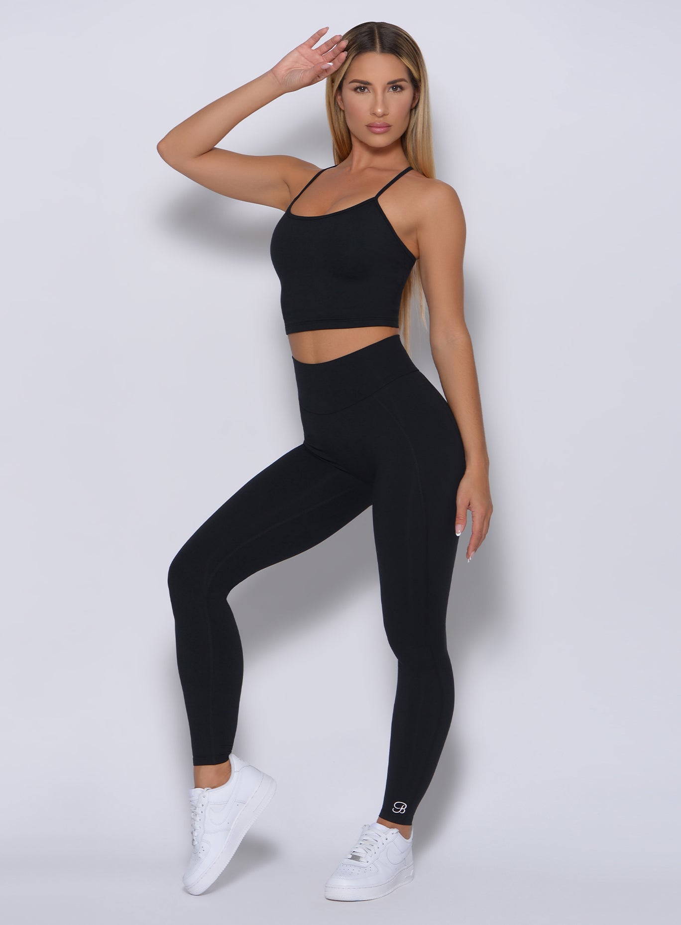 Front profile view of a model with her right hand on hair wearing our black uplift leggings and a matching bra