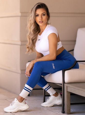 woman sitting down in blue leggings and white bombshell shirt