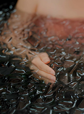 Person submerged in an ice bath filled with floating ice cubes during cold water therapy.
