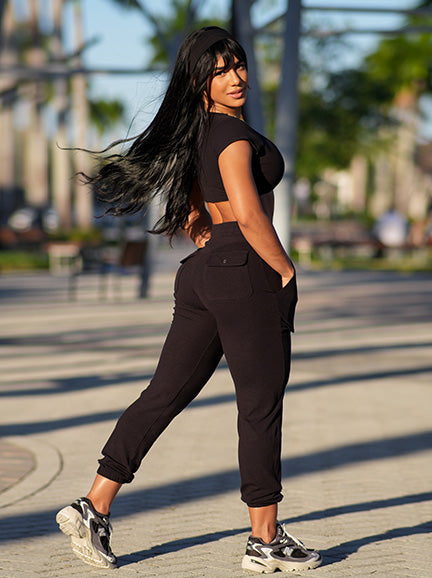 Model in black jogger suit outside.