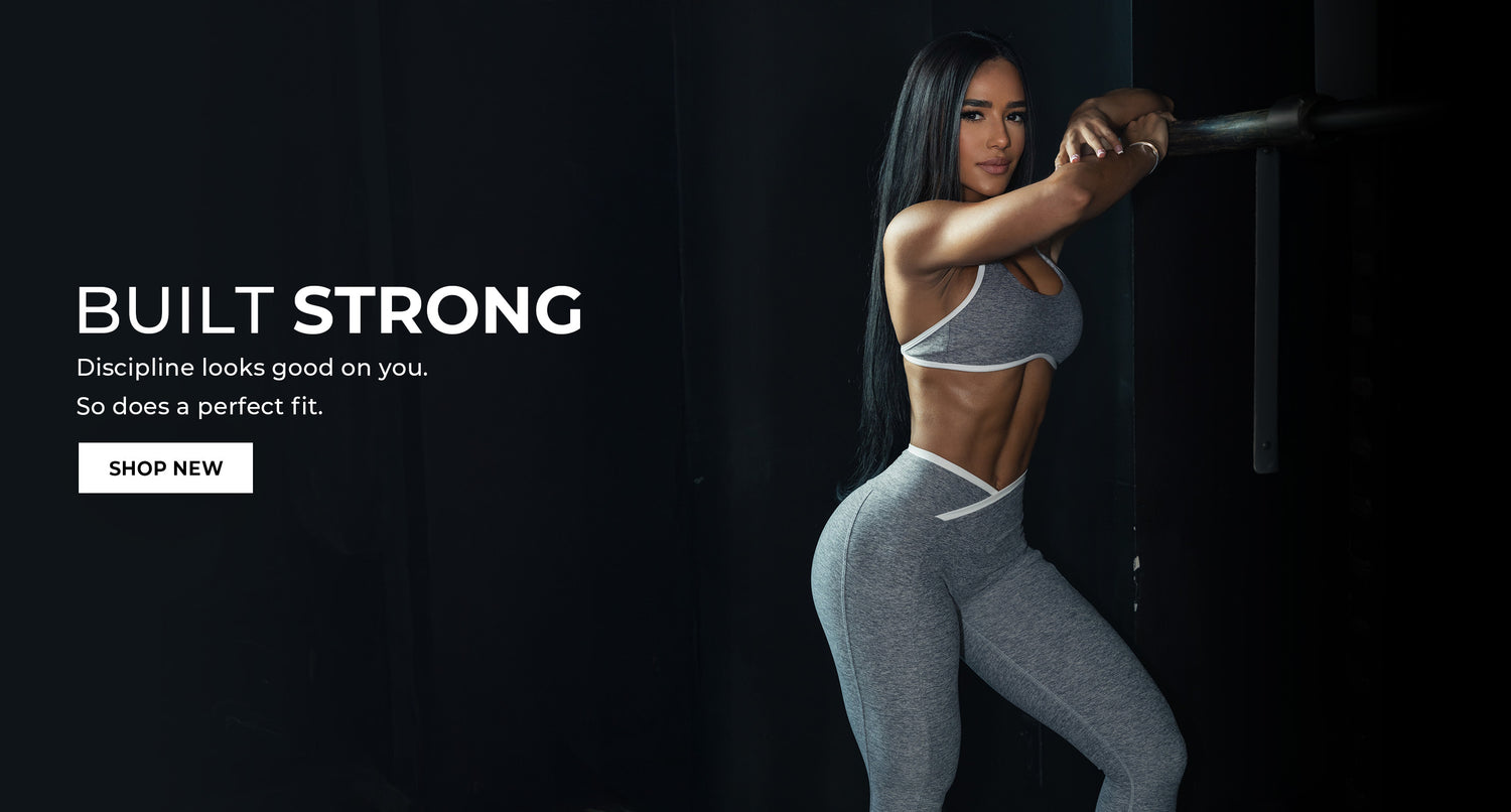 Woman in gray athletic wear with 'Built Strong' text and call to action on a dark background. She is wearing the Finish Line Bra and Line Contour Leggings in Cloud. Copy says "Built STRONG Discipline looks good on you. So does a perfect fit. Shop New"