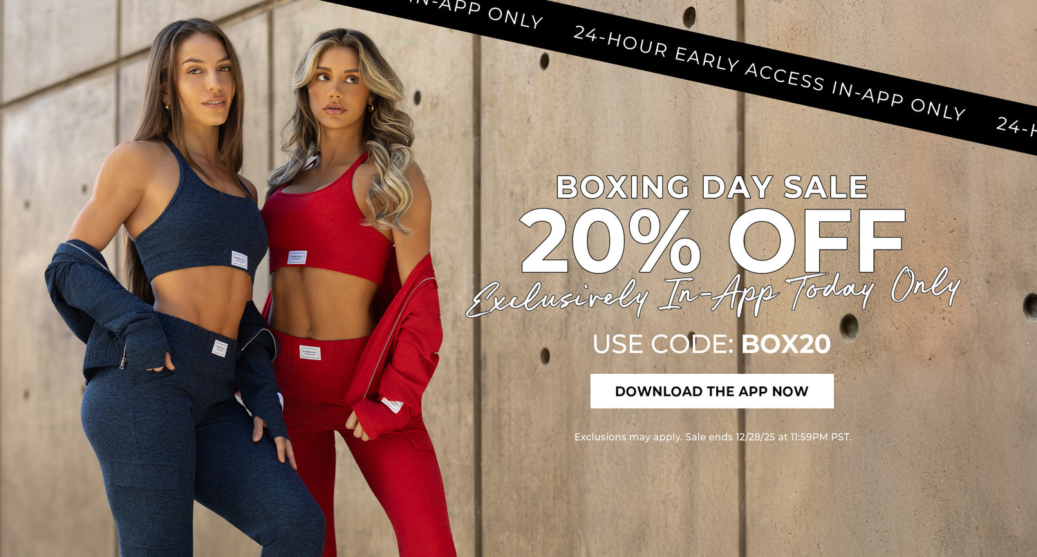 Two women in the Cloud Lounge sets. Model on the left is wearing the Sapphire Blue and the model on the right is wearing the Scarlet red set. This is a Boxing Day sale advertisement on a wooden background. Text in black banner says "24-hour early access in-app only" and white text below reads "BOXING DAY SALE 20% OFF EXCLUSIVELY IN APP TODAY ONLY. USE CODE: BOX20" CALL TO ACTION IN WHITE BOX WITH BLACK LETTERS SAYS "DOWNLOAD THE APP NOW" below says "exclusions may apply. sale ends 12/28/25 at 11:59pm PST"