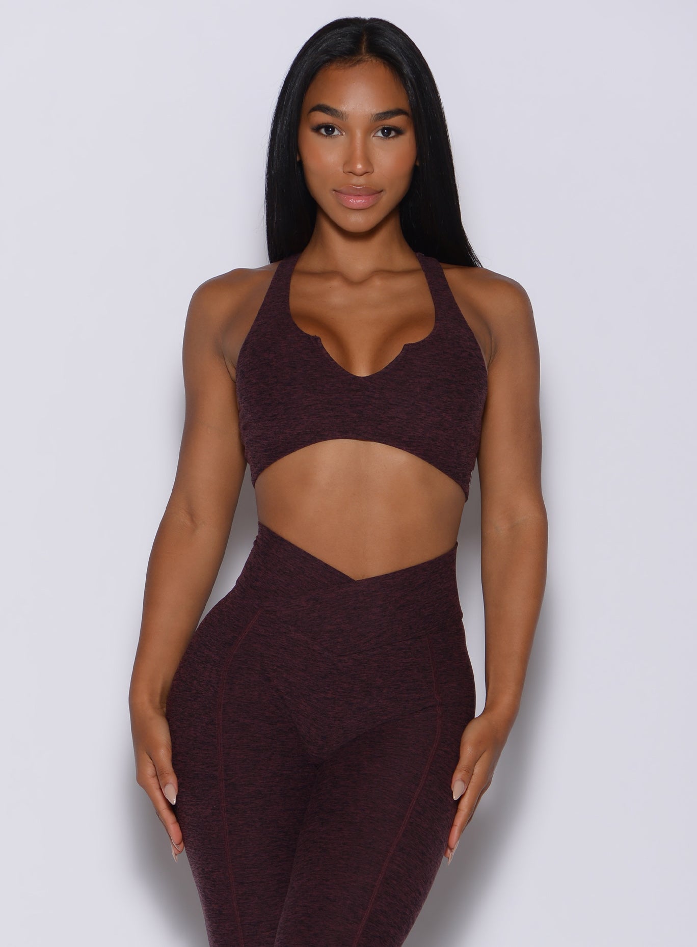 Front  profile view of a model wearing our ace sports bra in port color and a matching leggings