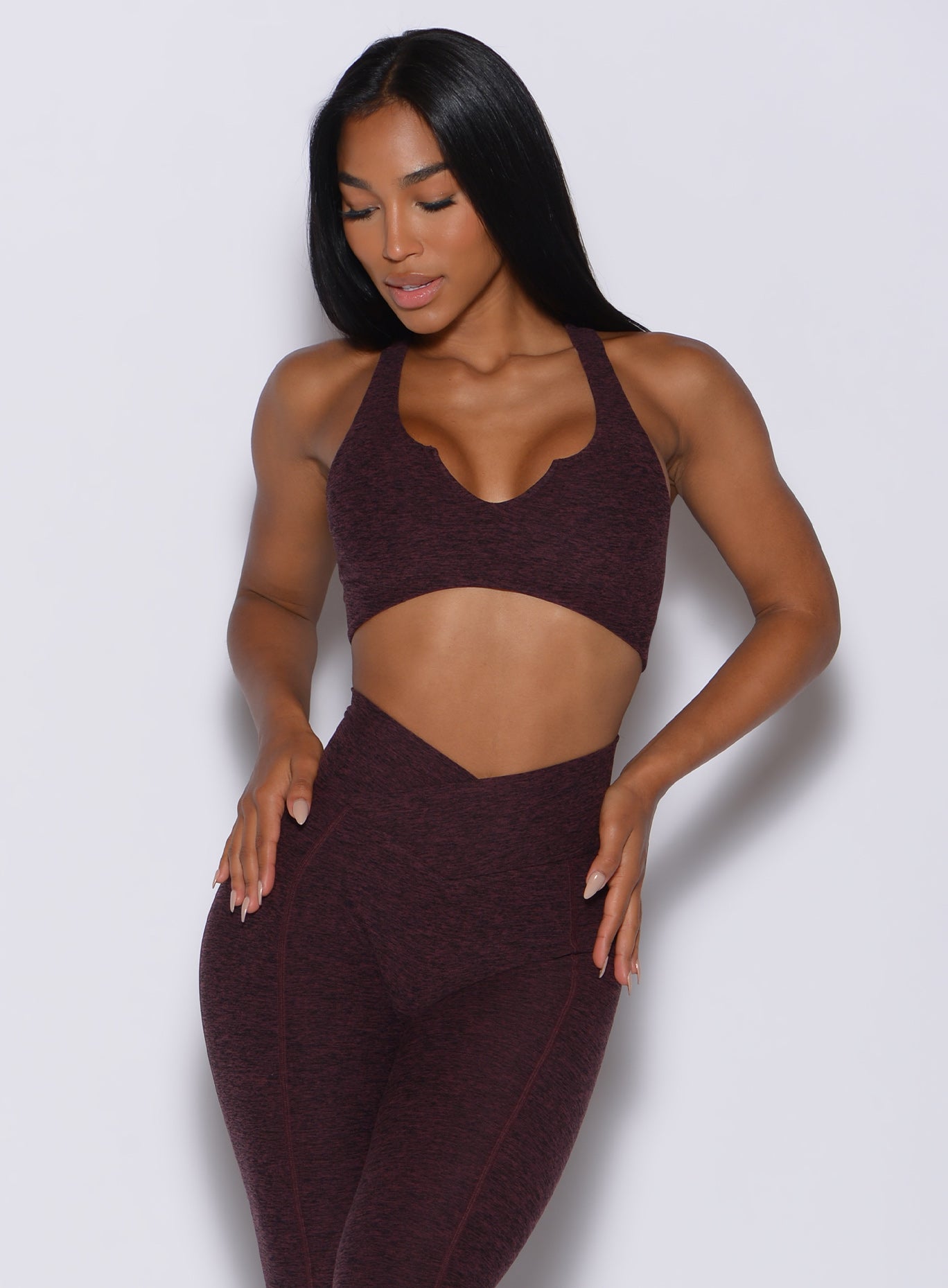 front profile view of a model in our ace sports bra in port color and a matching leggings