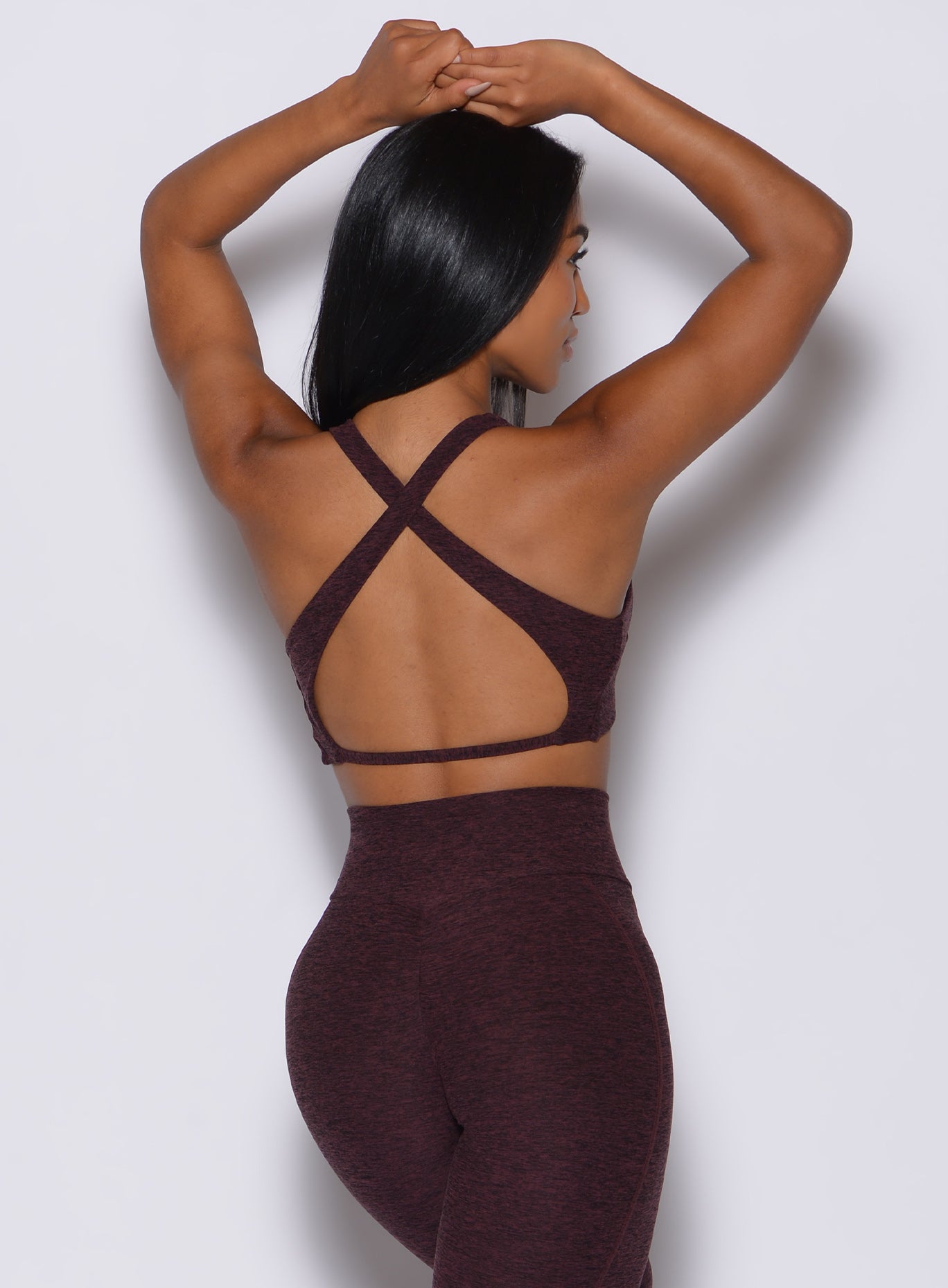 Back  profile view of a model in our ace sports bra in port color and a matching leggings