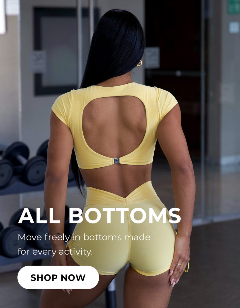 Model wearing a matching yellow cutout crop top and athletic shorts in a gym. Text reads 'ALL BOTTOMS – Move freely in bottoms made for every activity.' with a 'SHOP NOW' button.