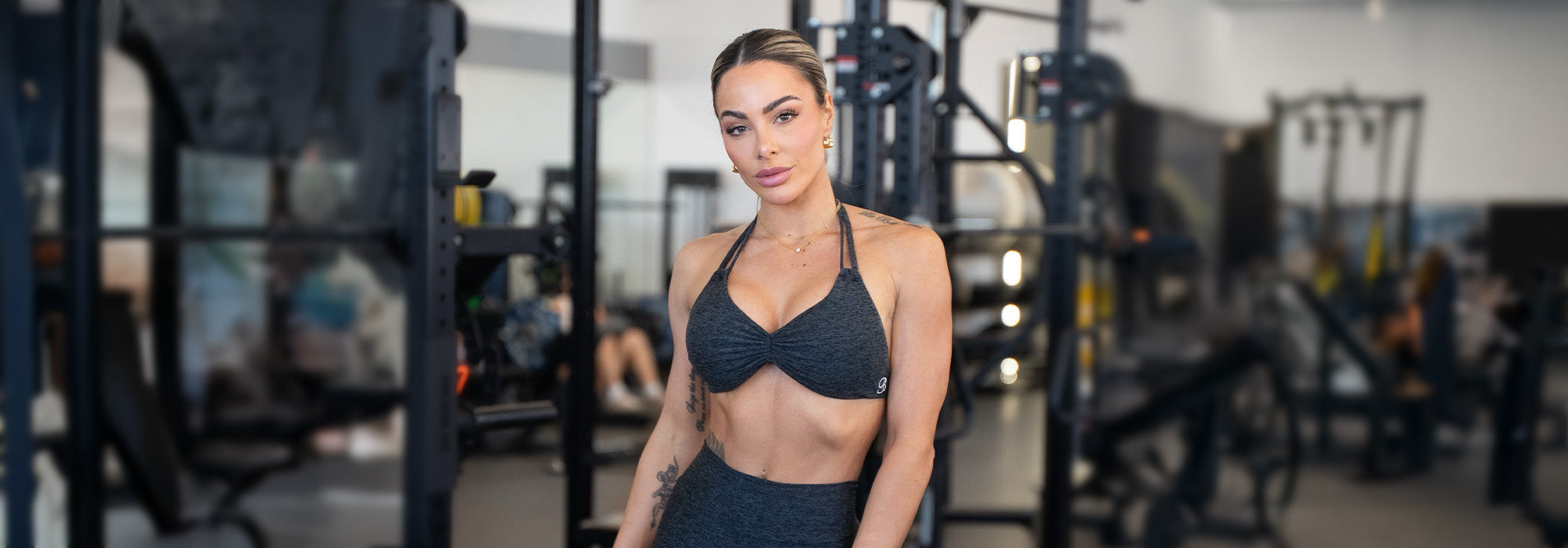 Woman in a black sports bra and leggings standing in a gym.