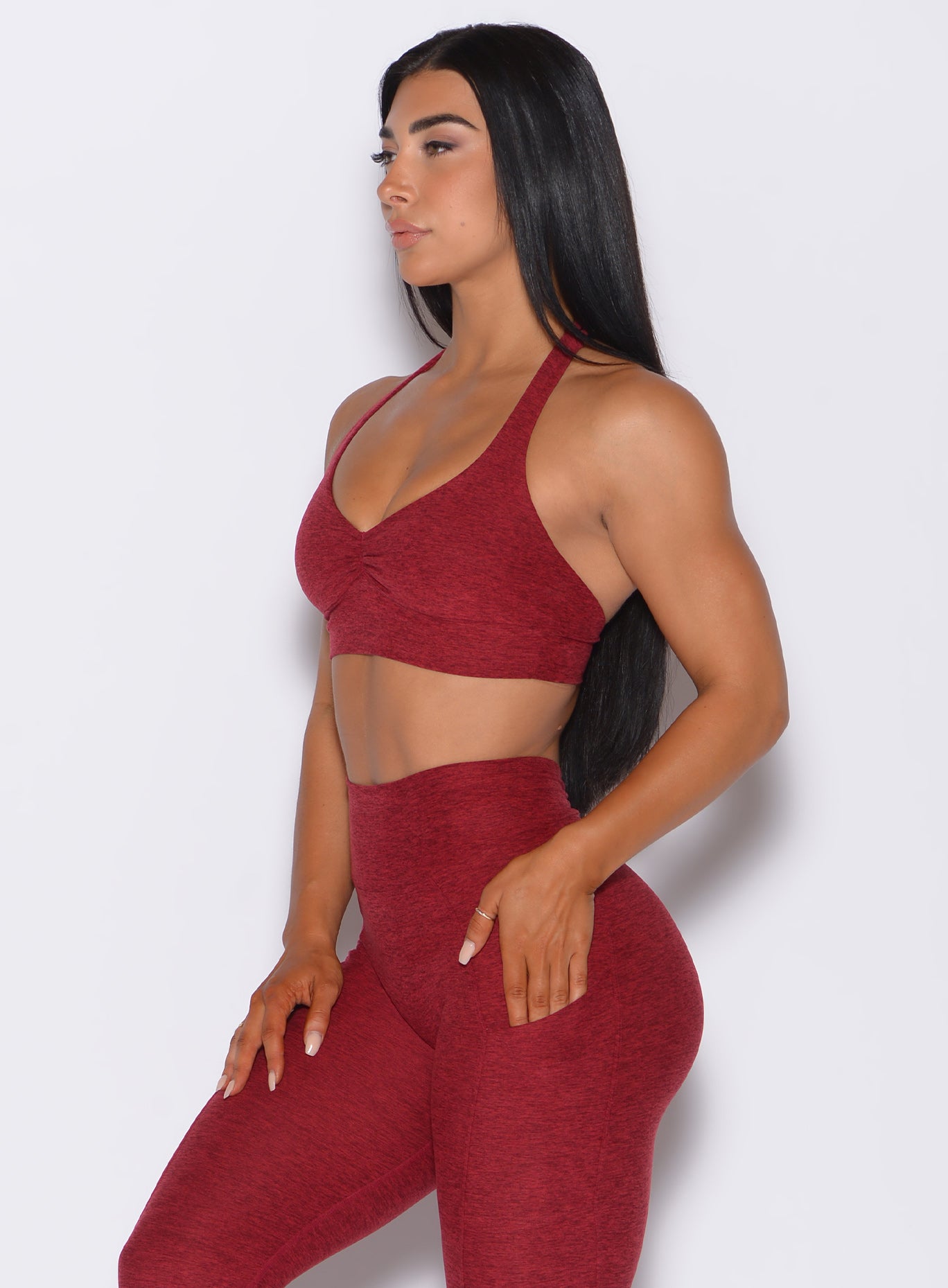 Left side profile view of a model wearing our backless bra in Garnet Red and a matching high waist leggings