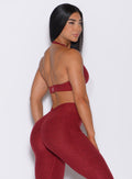 Left side back profile view of a model wearing our backless bra in Garnet Red and a matching high waist leggings