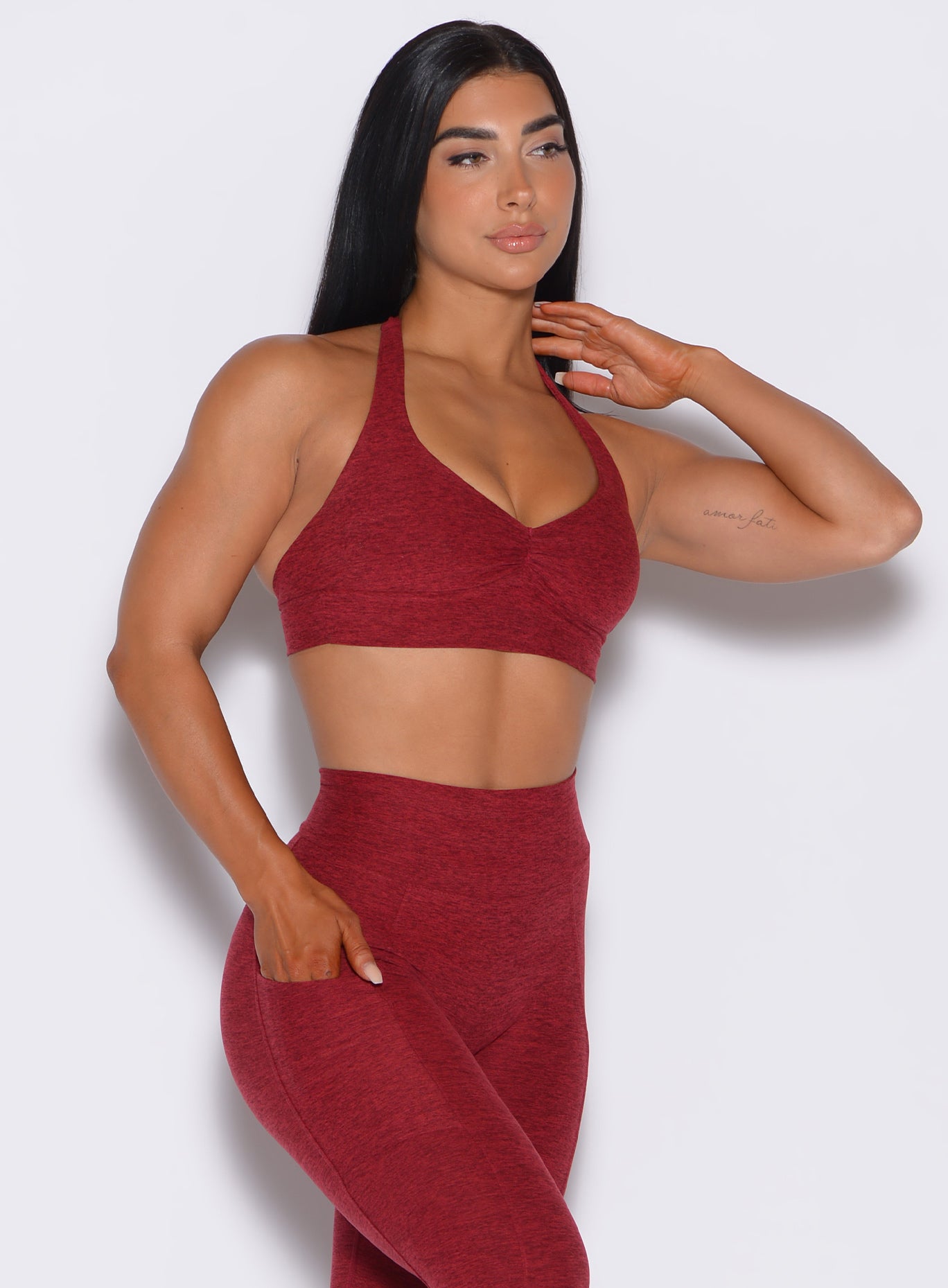 Right side profile view of a model angled right wearing our backless bra in Garnet Red and a matching leggings