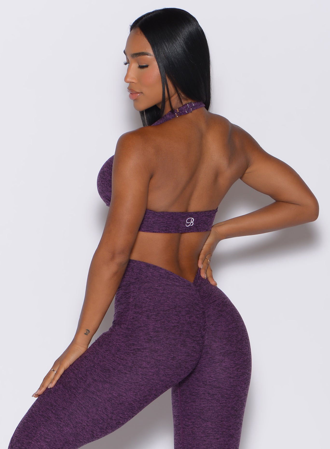 Back profile view of a model wearing our backless bra in Purple Passion color along with the matching leggings 