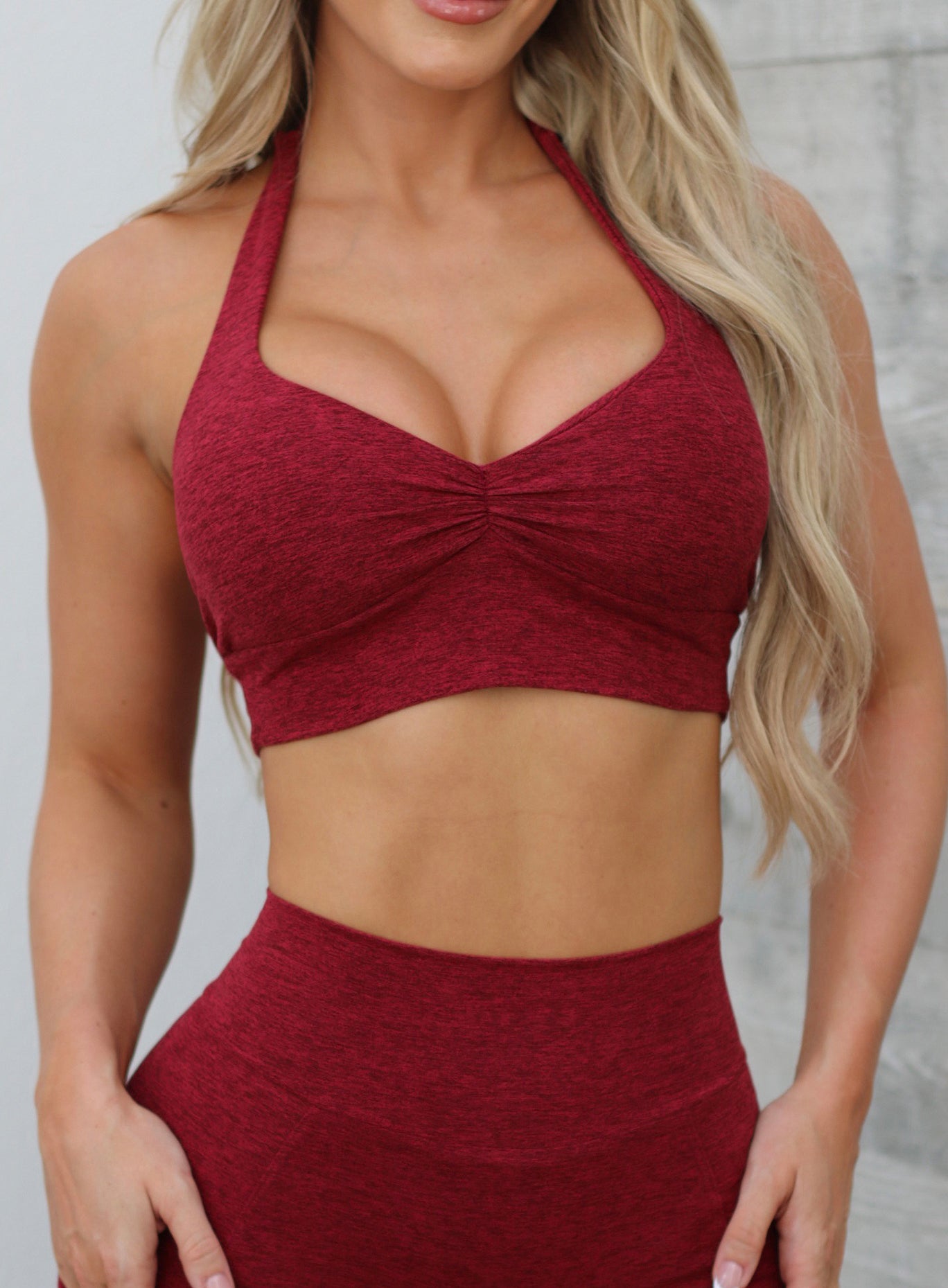 Front close up profile view of a model in our V Back Leggings in garnet red along with the matching bra 