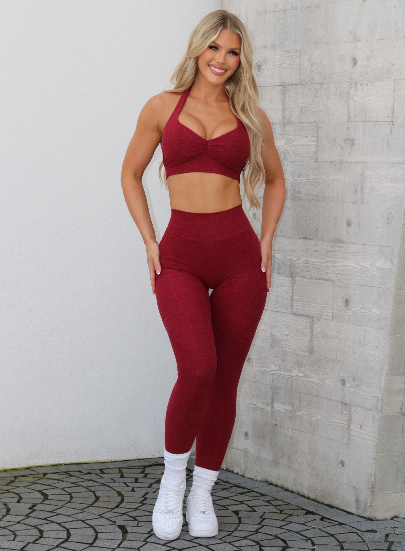 Front profile view of a model in our V Back Leggings in garnet red along with the matching bra