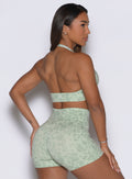 Back right side profile view of the model posing with one hand on her hip dressed in our Backless Bra in Leopard Cool Matcha paired with the matching shorts. 