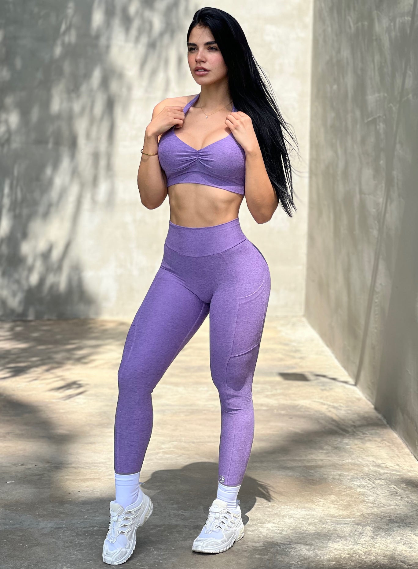 Front profile view of a model facing to her left wearing our V back leggings in violet color along with the matching bra