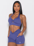 front profile view of a model with both hands inside the side pockets wearing the Backless Knot Bra in future dusk color paired with the matching shorts
