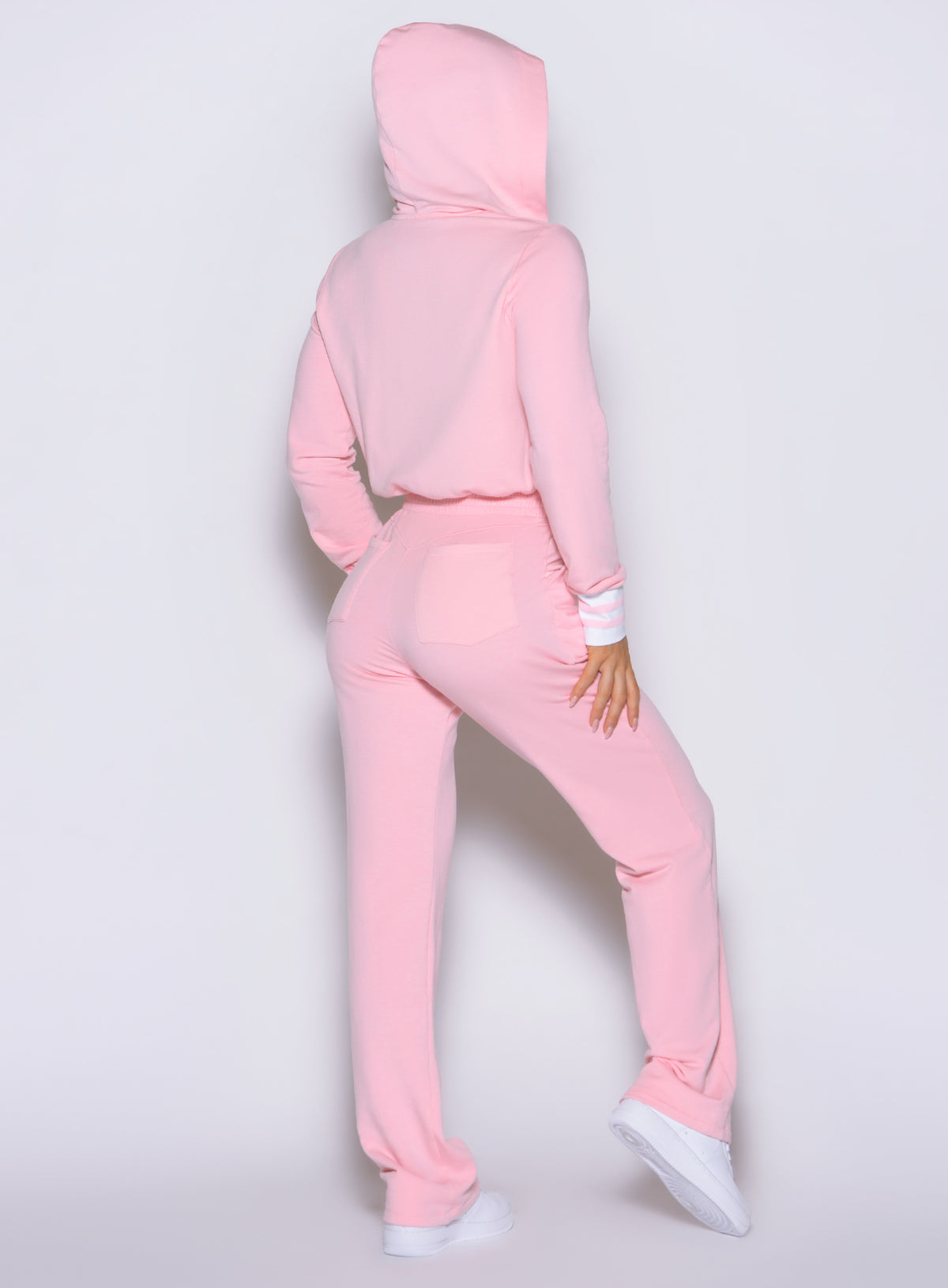 Rear perspective of the Believe Jumpsuit in Tickled Pink with hood up and straight-leg drape.