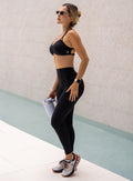 Left side view of a model in outdoors wearing the PocketBoost Leggings in Black color 