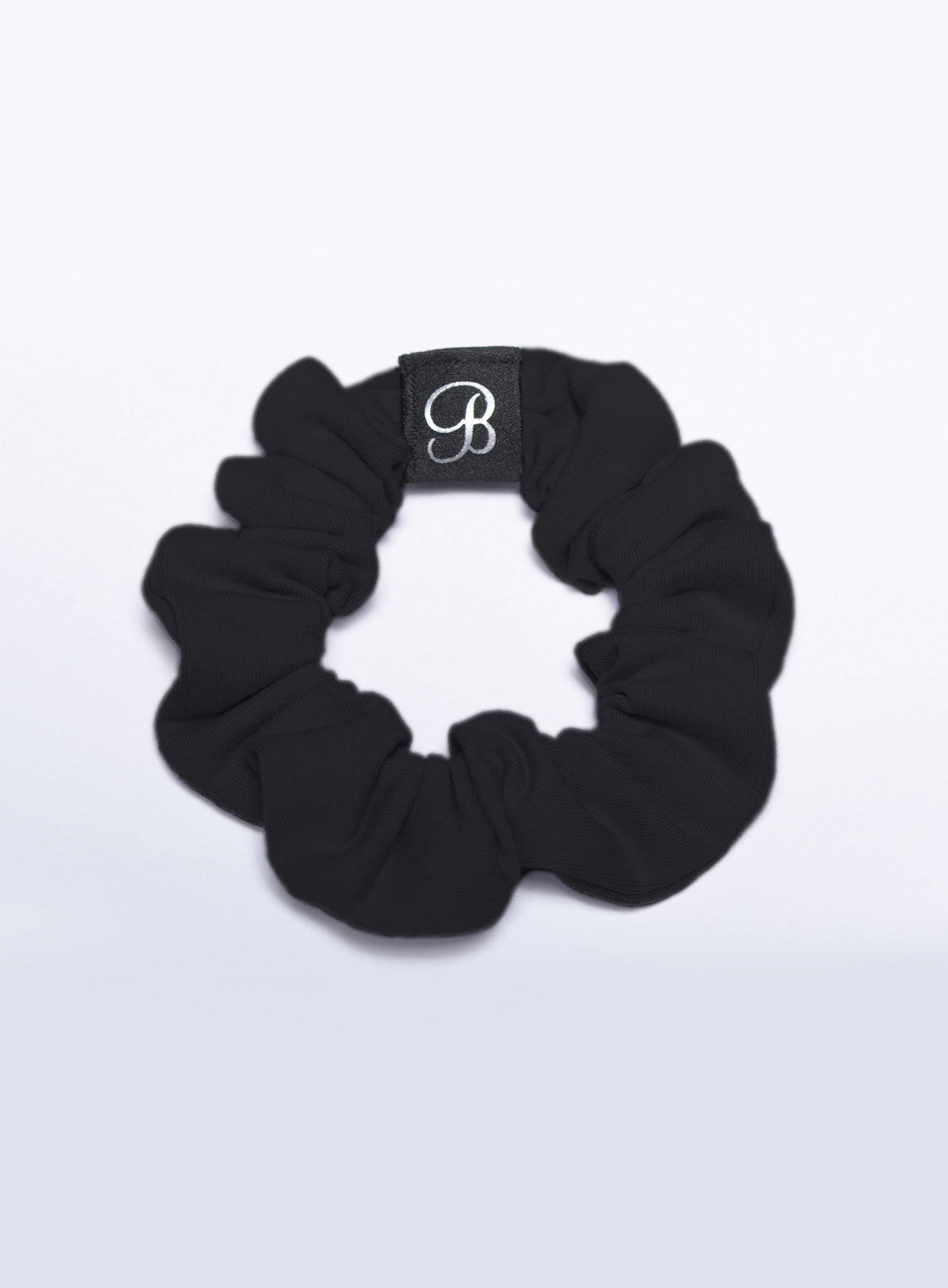 Black B Scrunchie hair accessory with soft stretch fabric and woven logo for secure gym styling.
