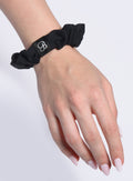 Picture of the B Scrunchie in Black color on the hand of a model