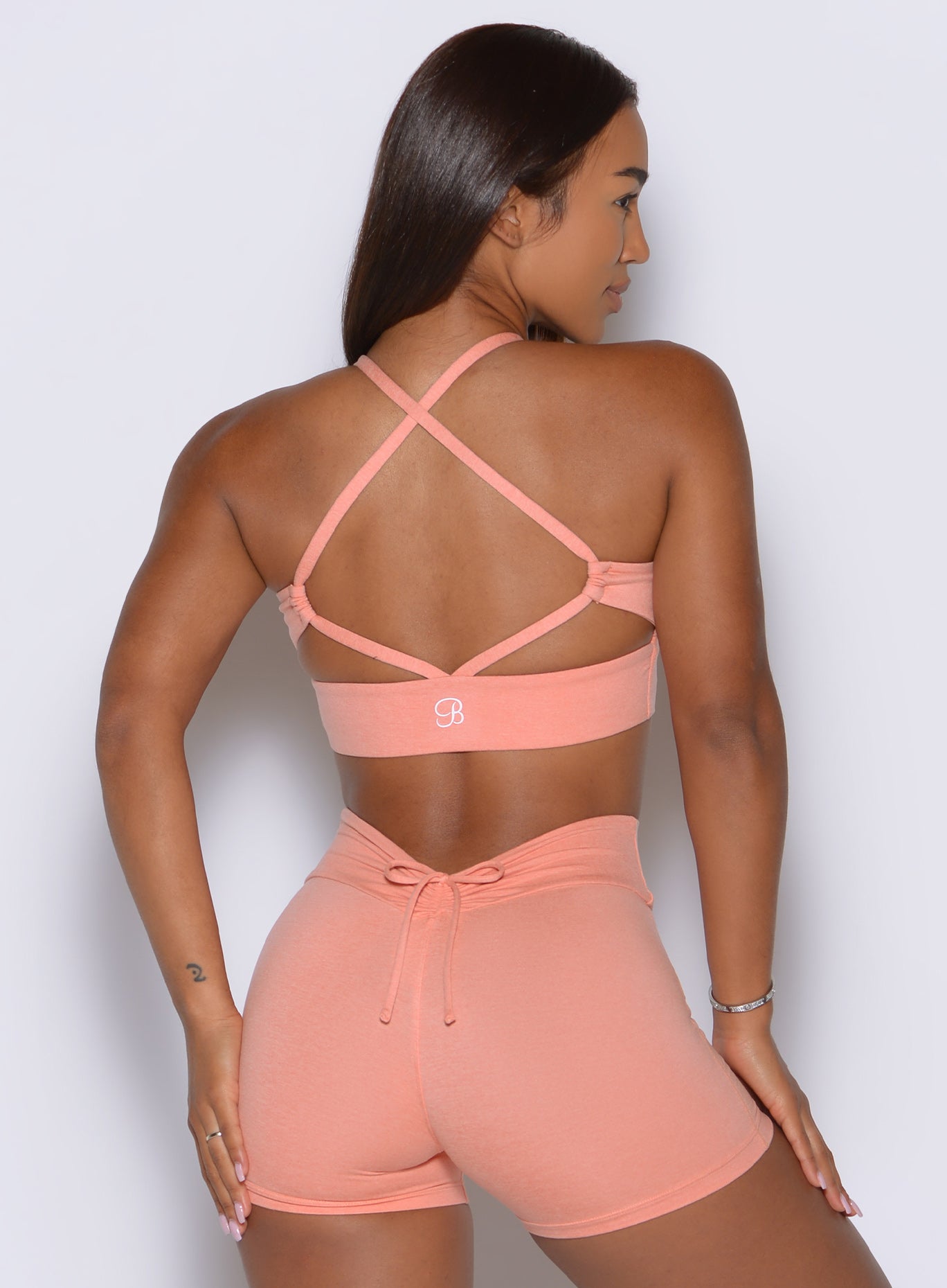 The open-back design pairs delicate crossover straps with a supportive elastic band