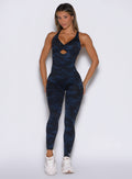 front profile view of a model with both hands resting on her thighs wearing the Bombshell Bodysuit in Blue/Black camo color