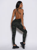 back profile view of a model facing to the right side wearing the Bombshell Bodysuit in Green/Black camo color
