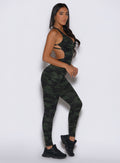 right side profile view of a model wearing the Bombshell Bodysuit in Green/Black camo color