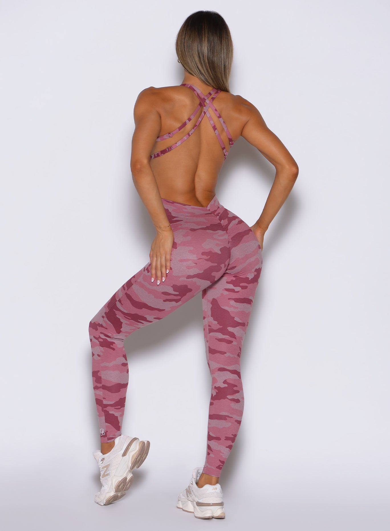 back profile view of a model wearing the Bombshell Bodysuit in Hibiscus camo color