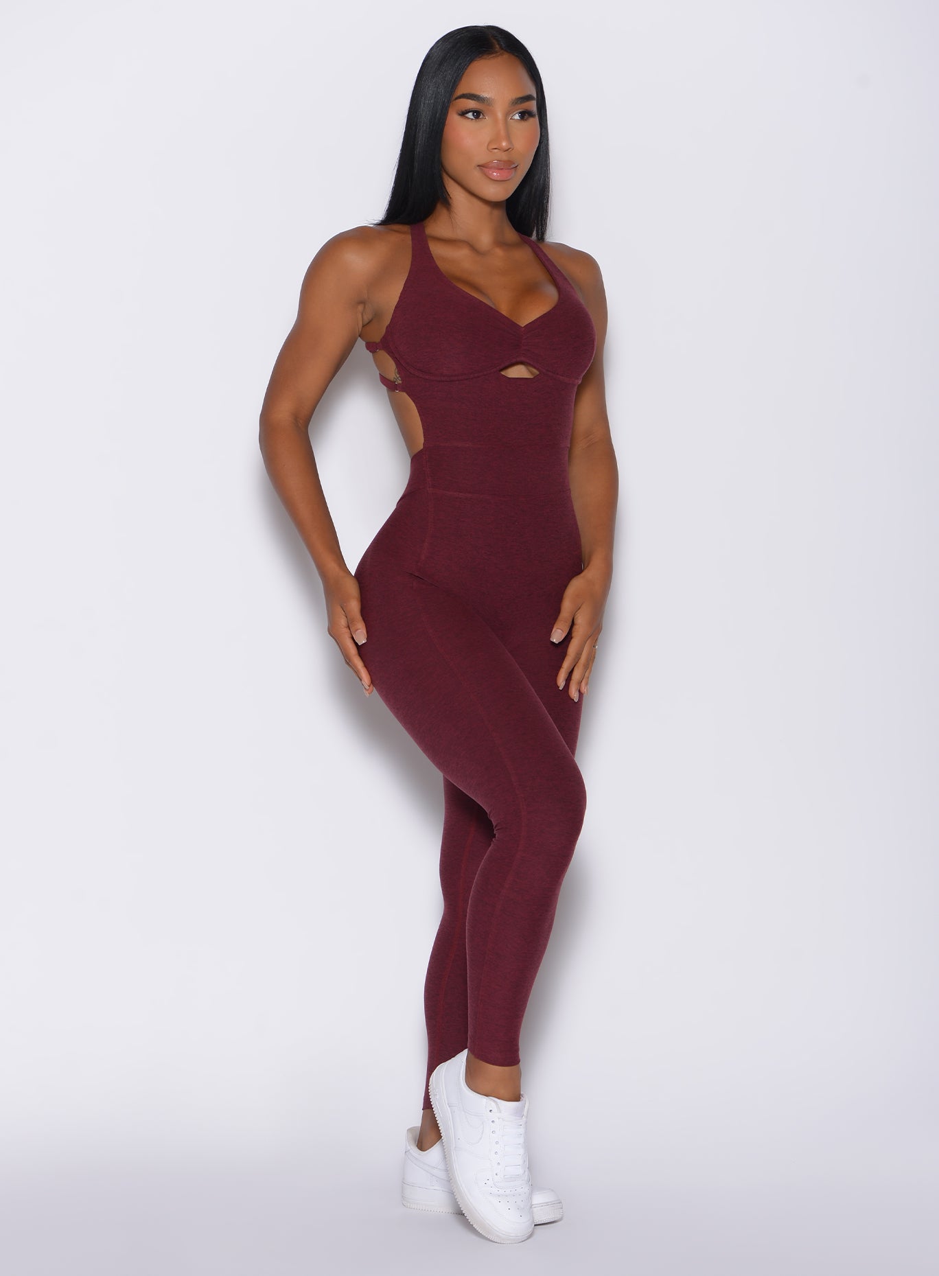 Right side profile view of a model angled right wearing our bombshell bodysuit in red wine color