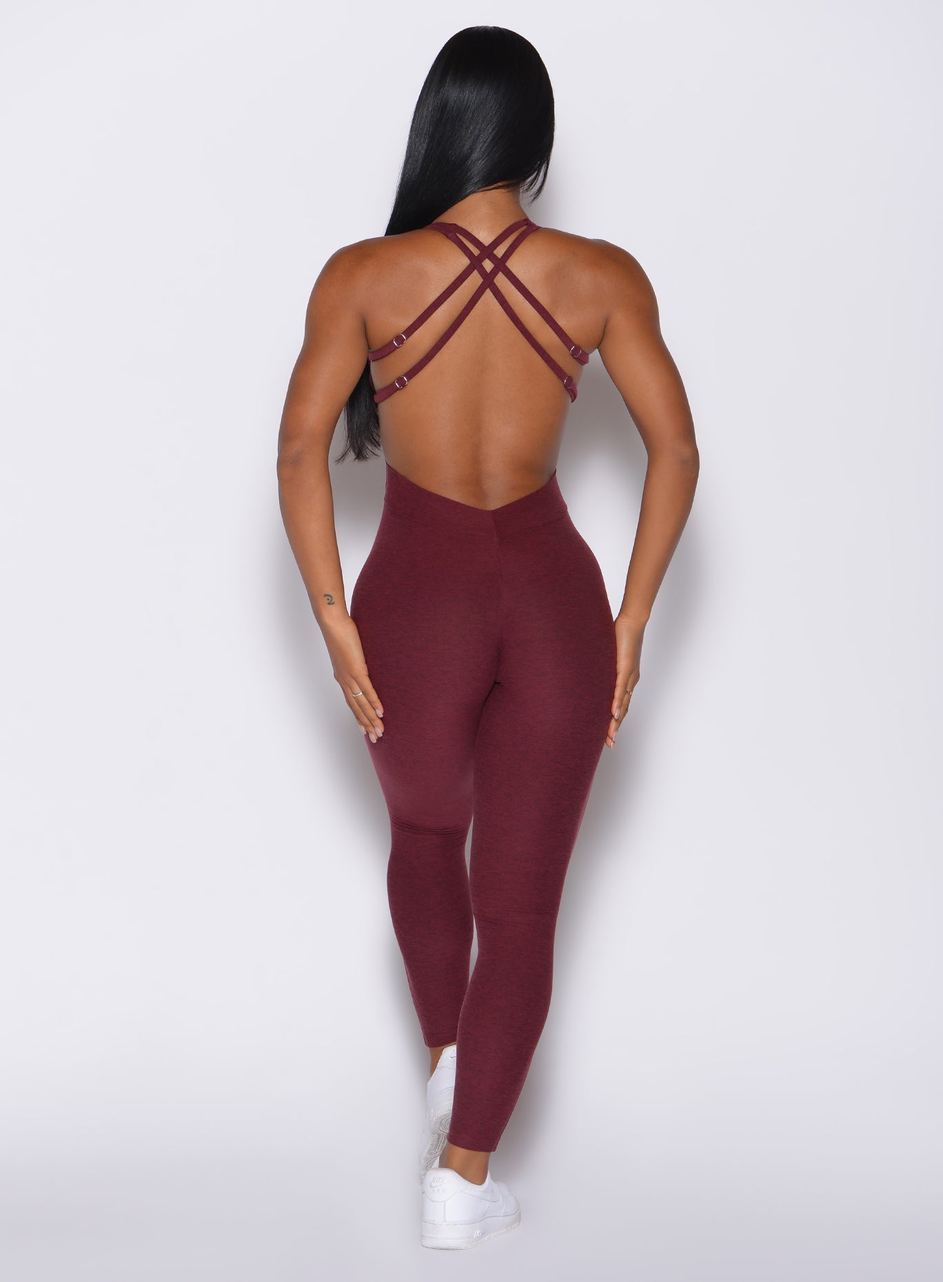 Back profile view of a model wearing our bombshell bodysuit in red wine color