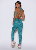 back profile view of a model looking over her shoulder wearing the Bombshell Bodysuit in Teal camo color