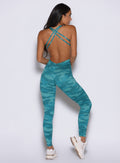 back profile view of a model facing to the right side wearing the Bombshell Bodysuit in Teal camo color