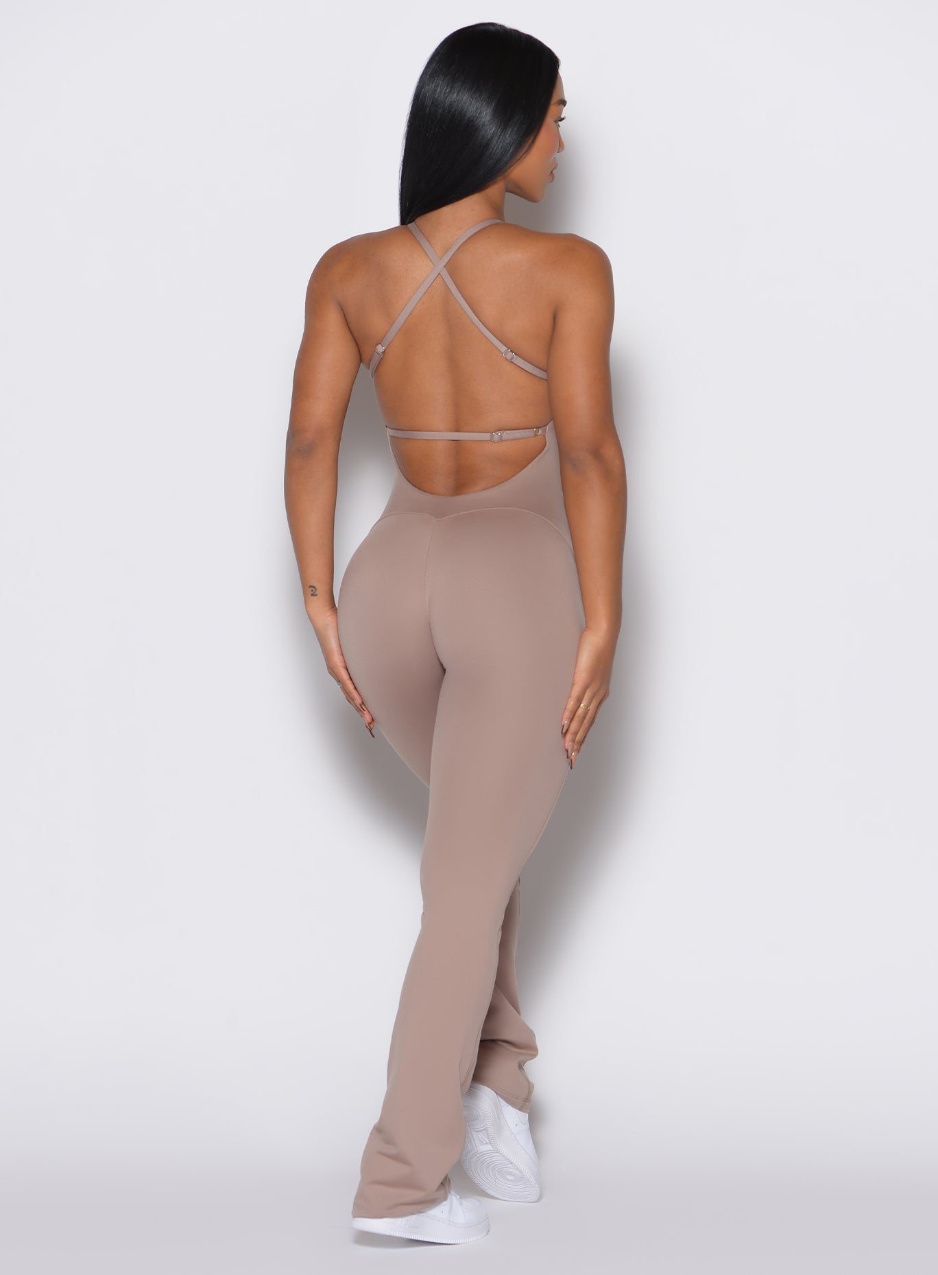 Back profile view of a model facing right wearing the Bombshell Bunny Bodysuit in Clay color.